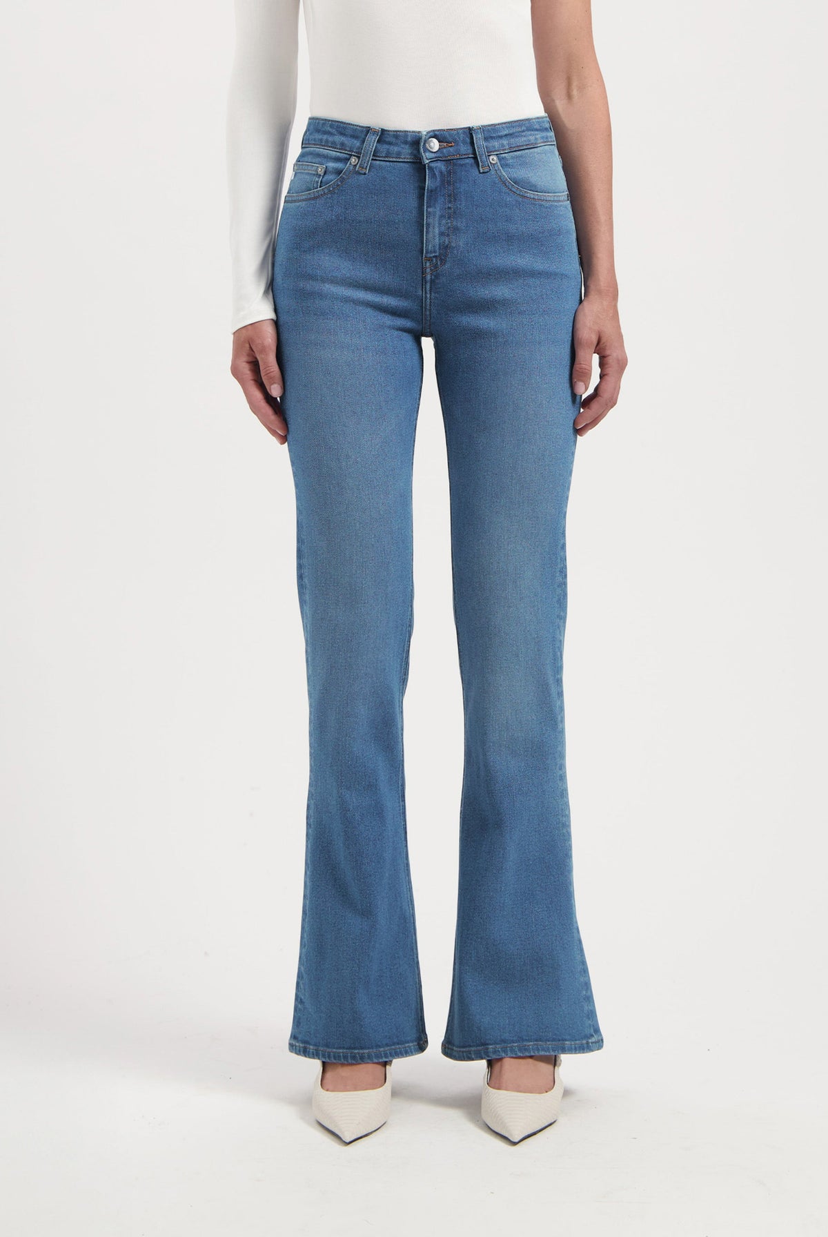 High-waisted, light blue flared jeans paired with a long-sleeve white top, showcasing a stylish casual outfit.