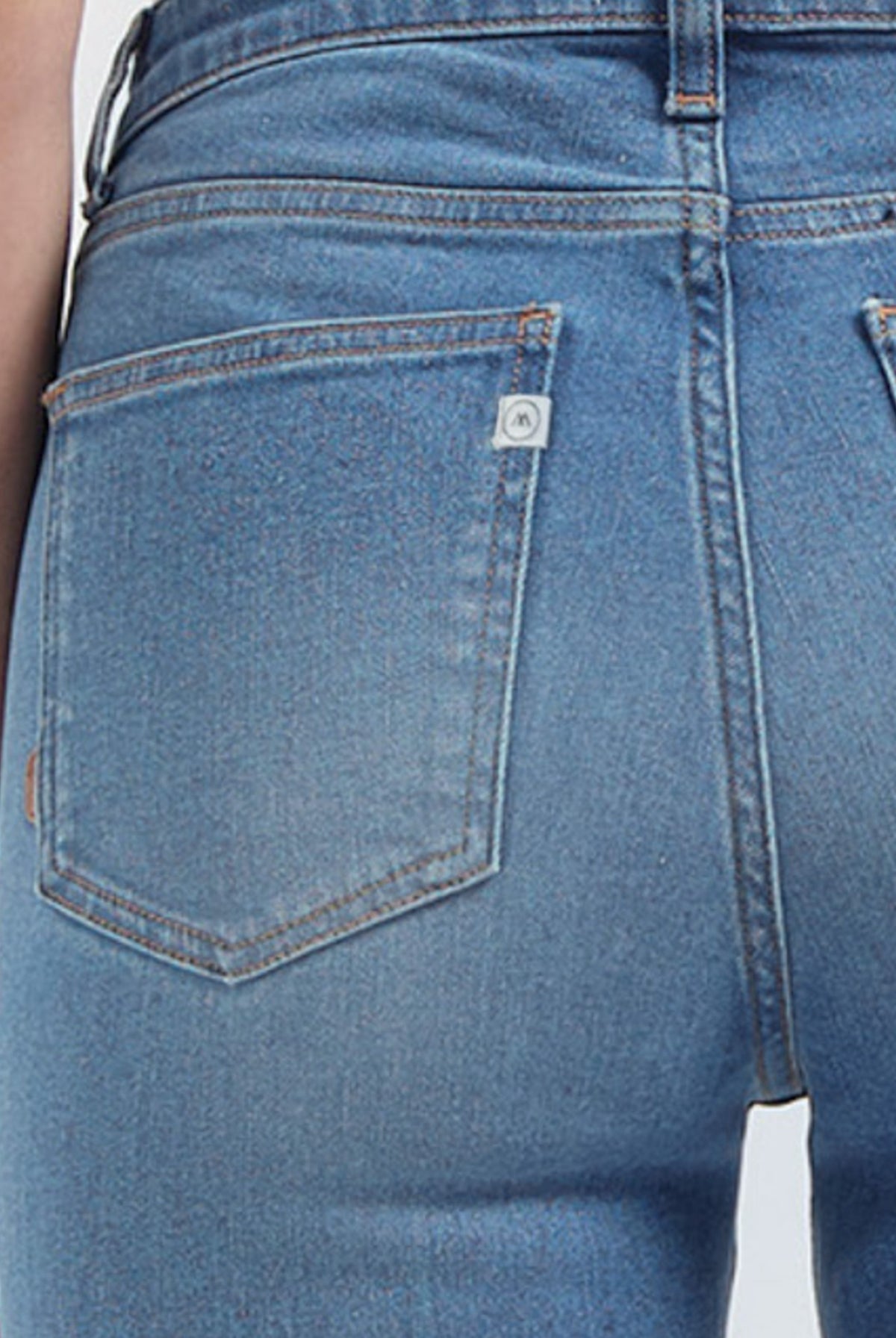 Close-up of light blue denim jeans with visible back pocket stitching and a subtle logo tag near the waistband.