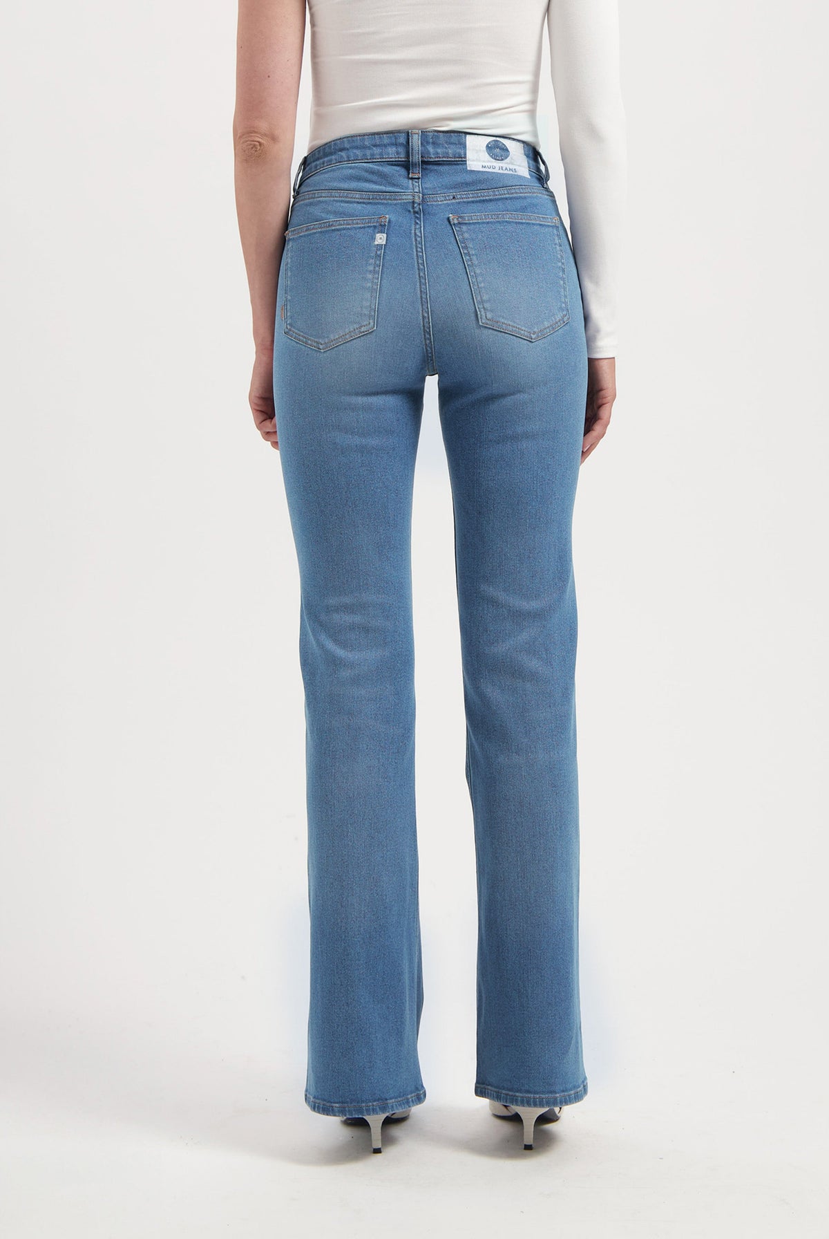 Back view of a person wearing MUD Jeans, sustainable blue denim with a straight-leg fit, paired with a simple white top.
