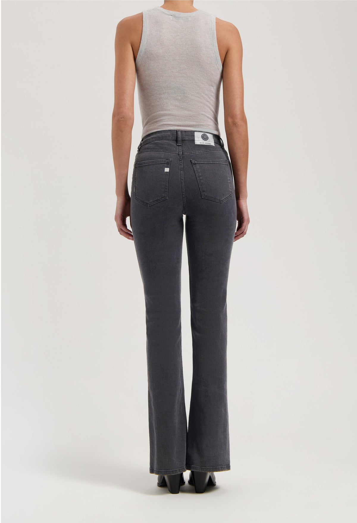 Back view of gray, high-waisted flare jeans from MUD Jeans, paired with a fitted sleeveless light gray top.