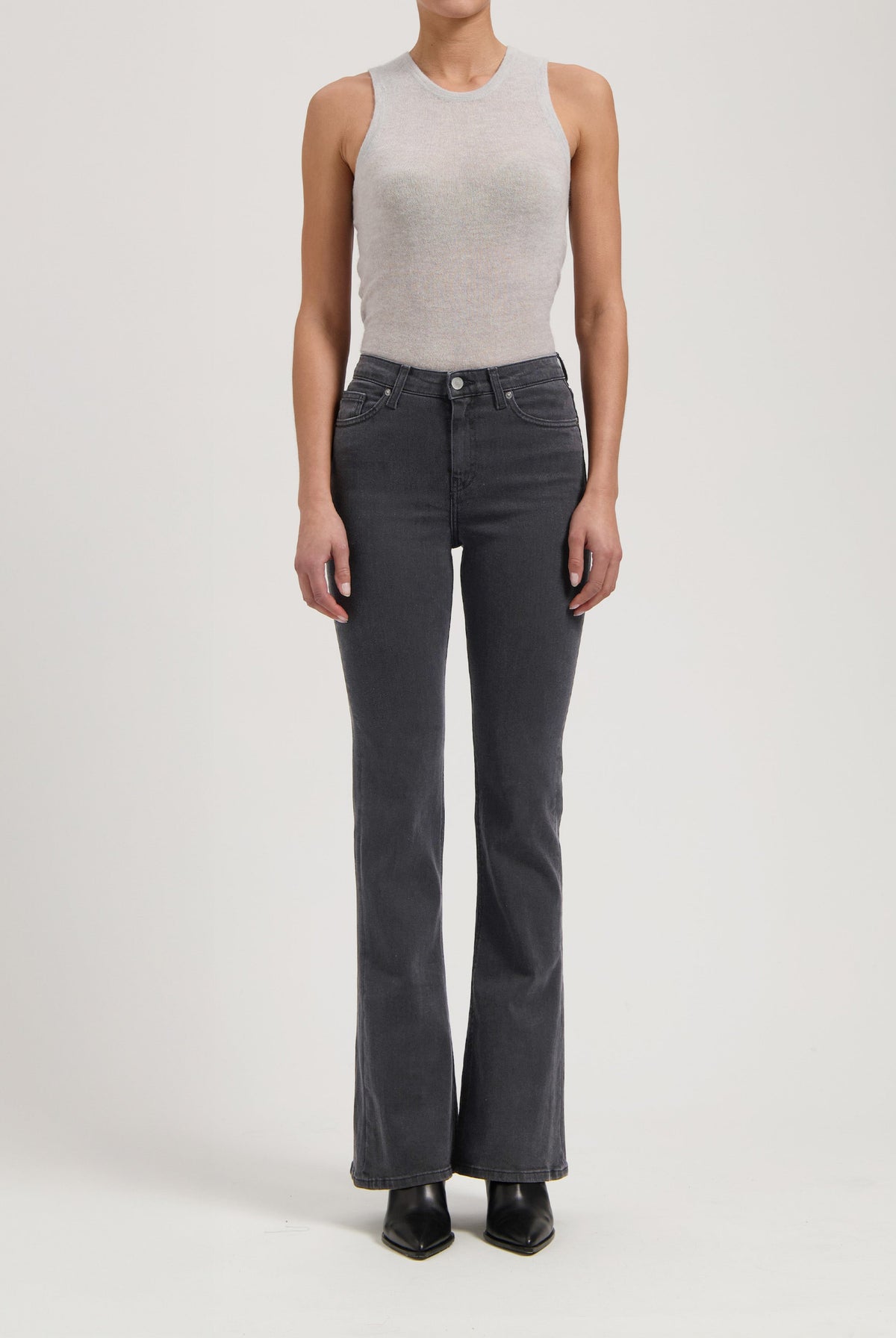 Gray sleeveless top paired with high-waisted black denim jeans, showcasing a minimalist and modern fashion style.