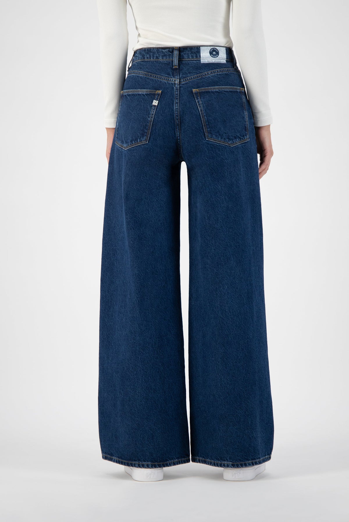 Wide-leg blue denim jeans with high waist, showcasing rear pockets, worn with a white ribbed long-sleeve top.