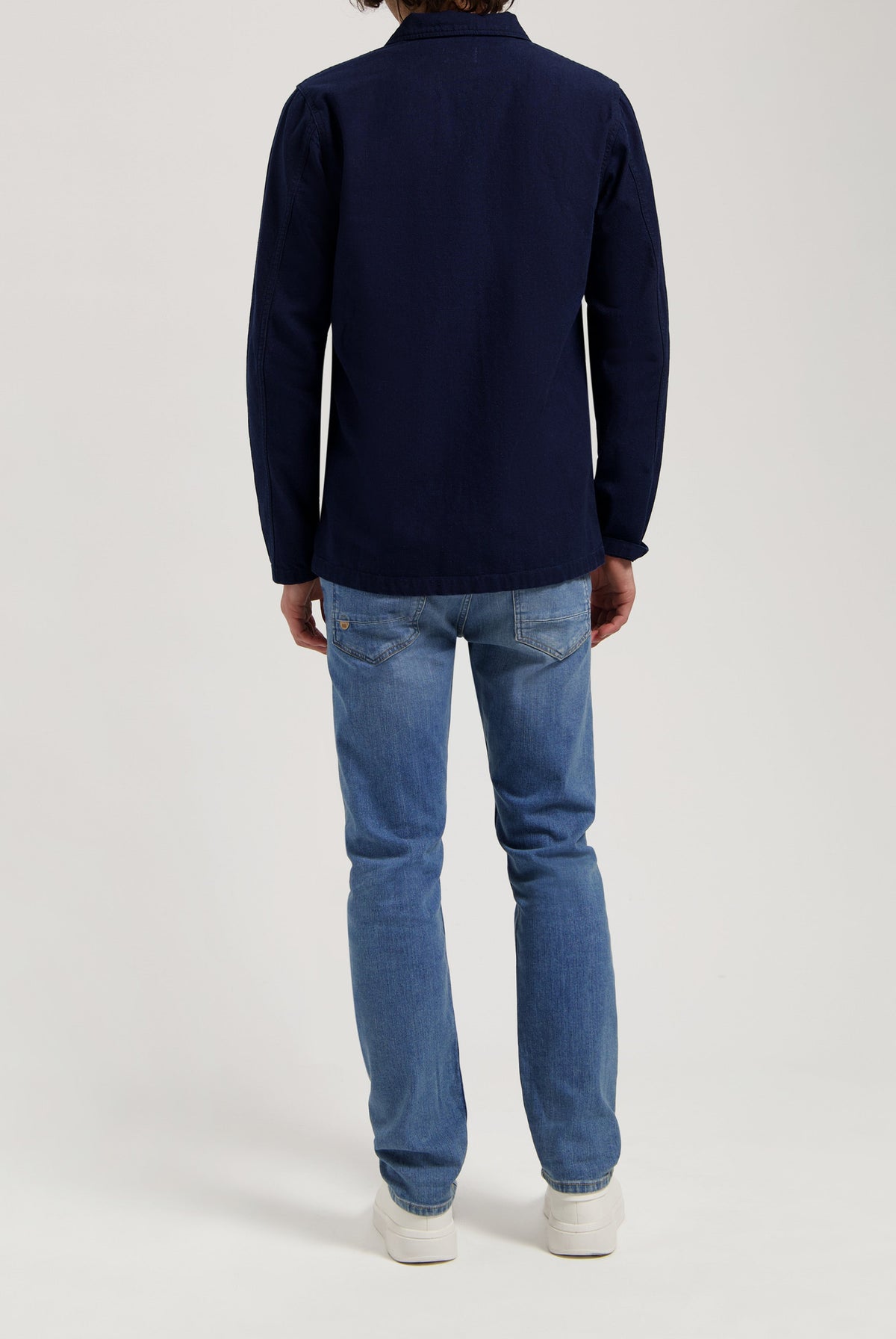 Sustainable MUD Jeans in classic fit, crafted from eco-friendly fabric, light blue denim paired with ivory knit sweater.