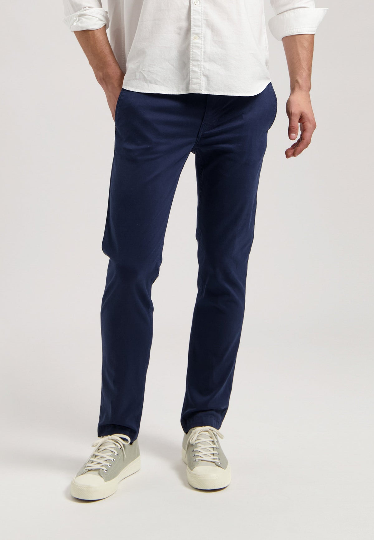 Sustainable MUD Jeans in dark gray denim, crafted ethically, paired with black sneakers and a black T-shirt.