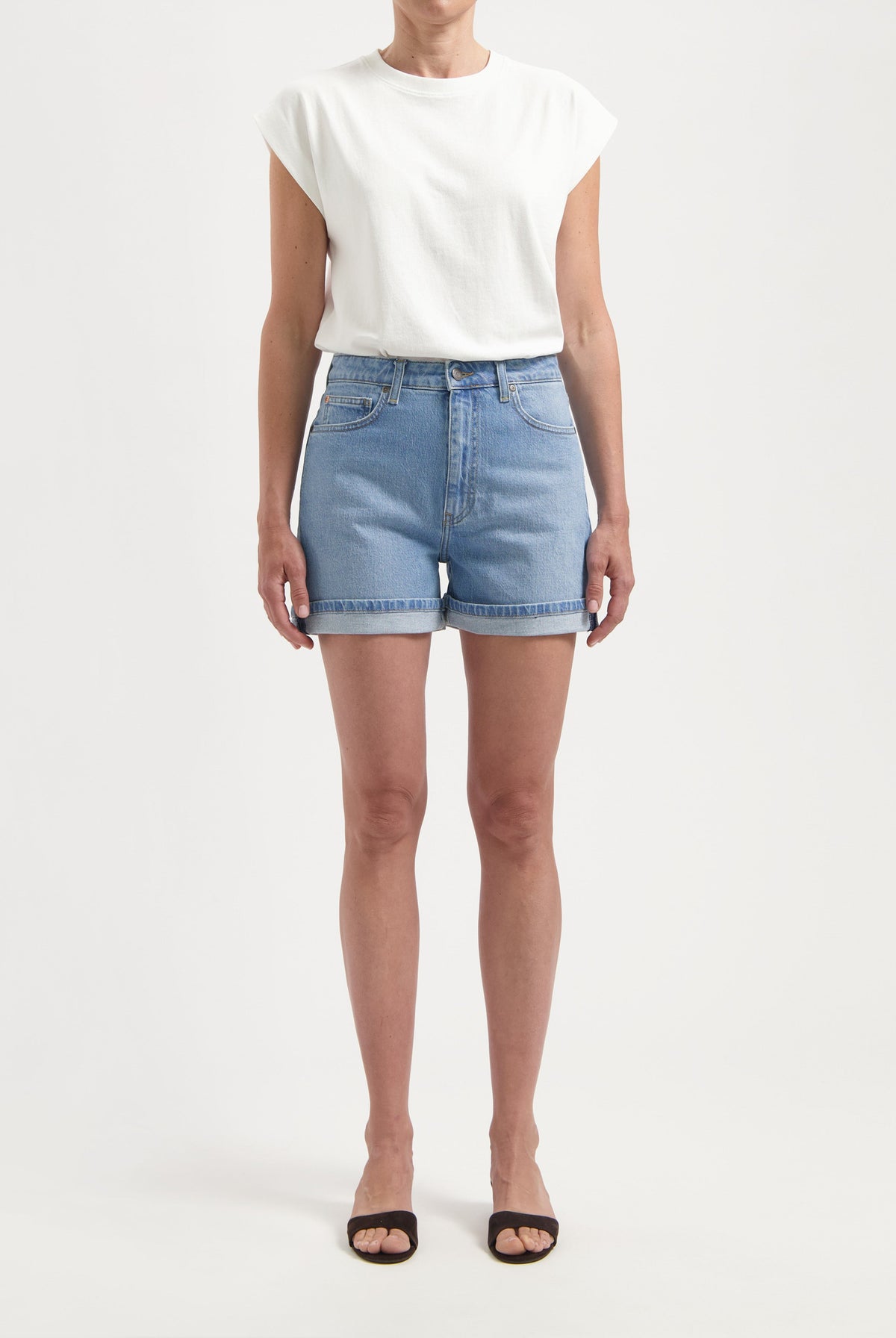 Light blue denim shorts paired with a casual white sleeveless top and black open-toe sandals for a fresh summer look.