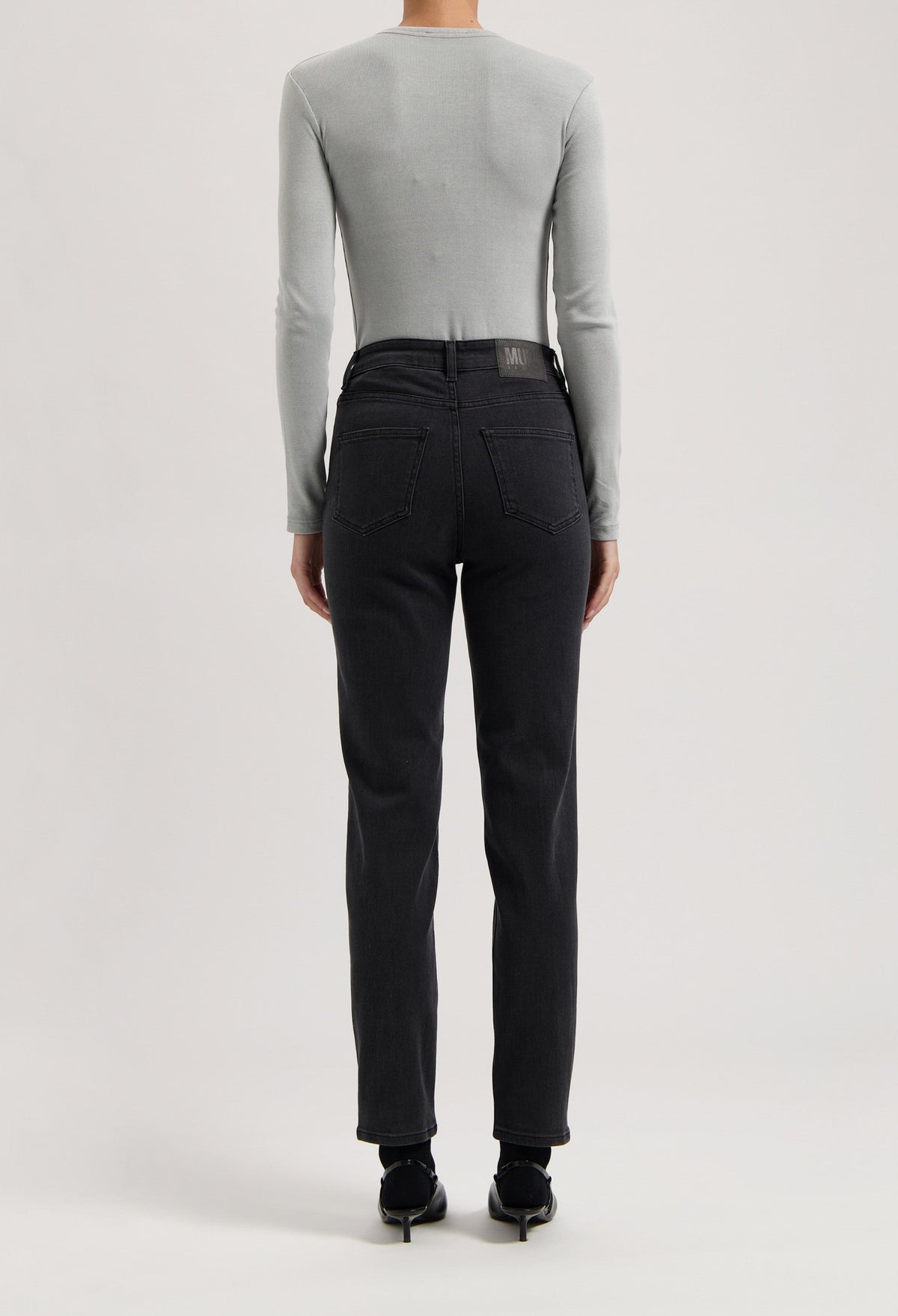 Light gray long-sleeve top paired with modern black denim jeans, showcasing a sleek and minimalist casual look.