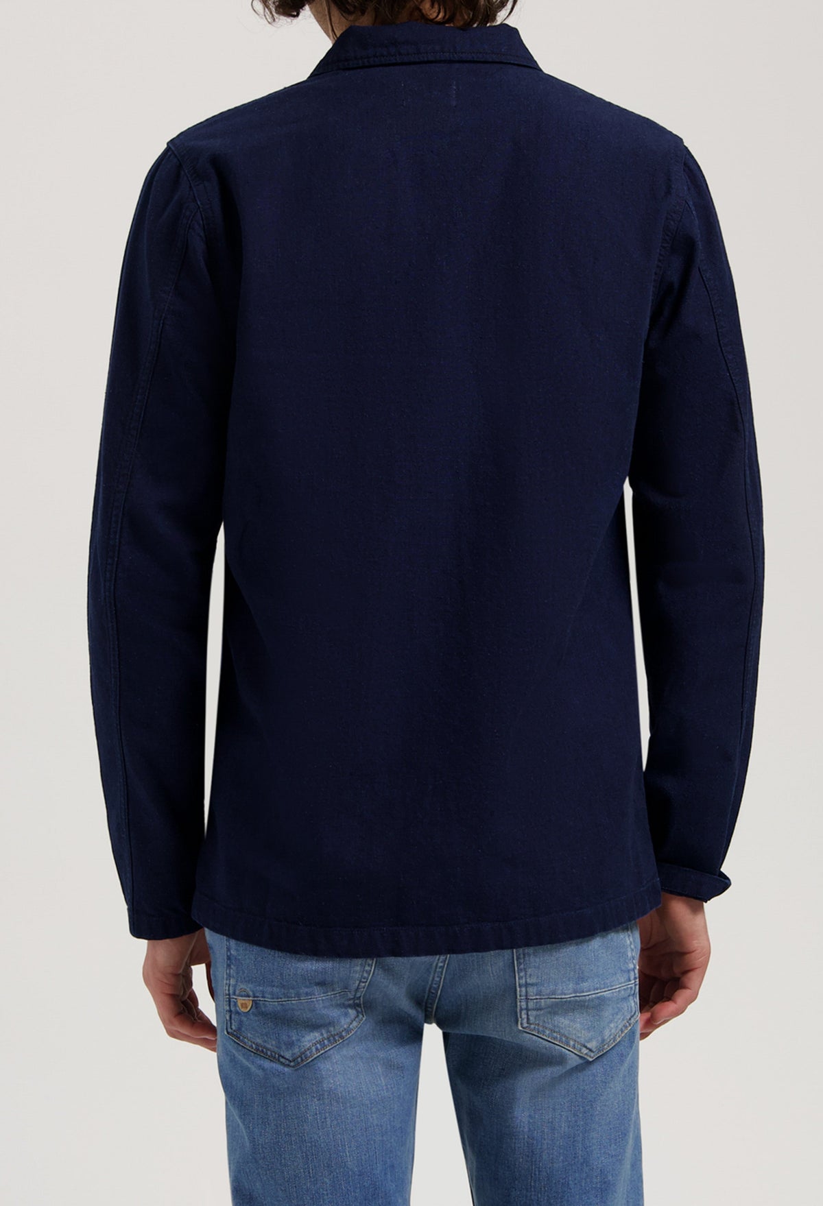 Sustainable MUD Jeans crafted from organic cotton, featuring blue denim in a relaxed fit, styled with a black jacket.