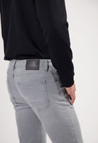 Sustainable MUD Jeans made from organic cotton, classic blue denim, paired with a gray sweater and beige sneakers.