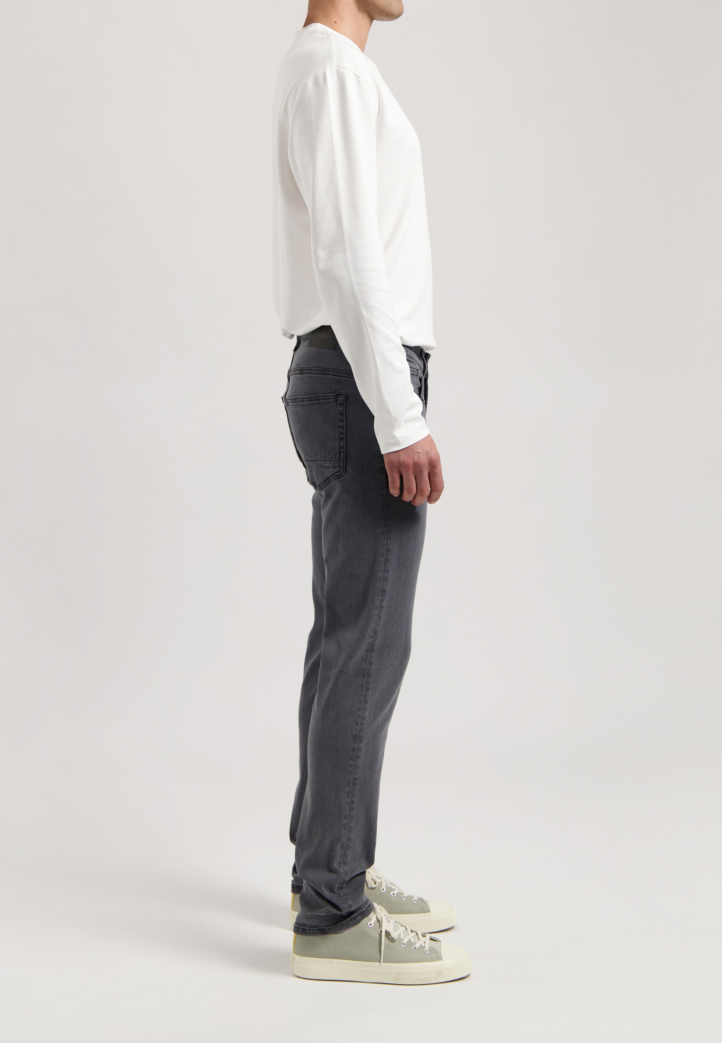 Sustainable MUD Jeans in dark denim, crafted from ethical materials, paired with a light gray sweater.