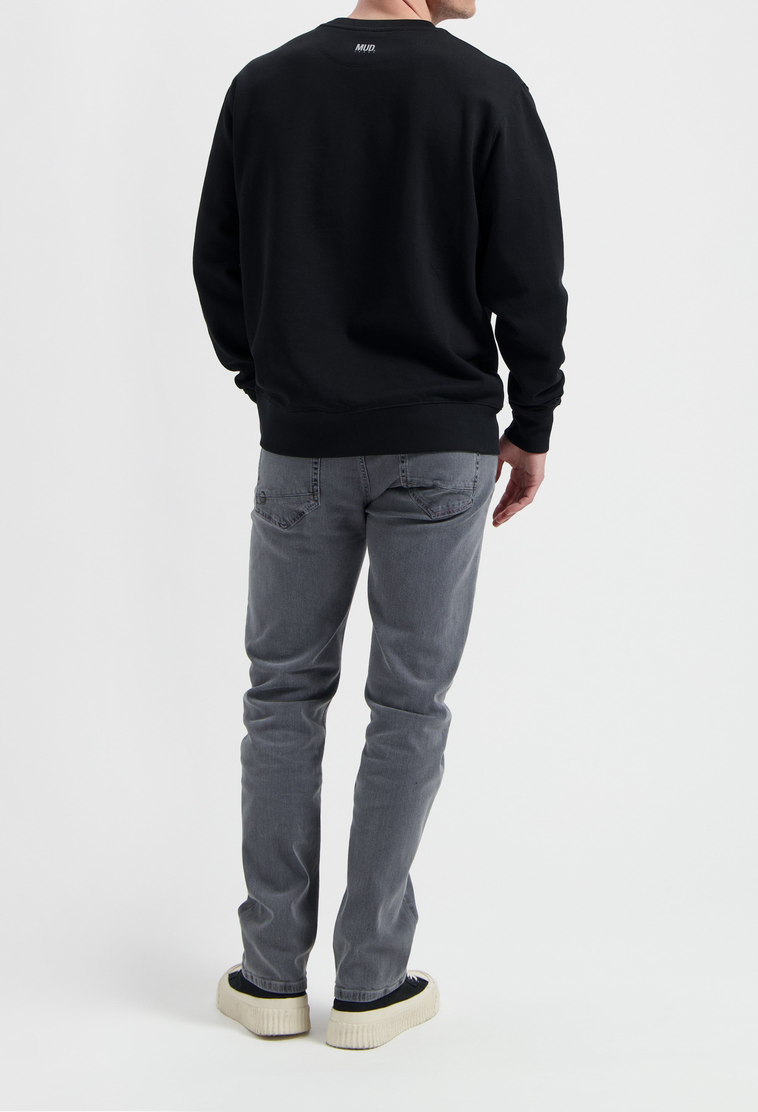 Sustainable MUD Jeans in gray denim, showcasing ethical fashion with a comfortable fit paired with a black sweatshirt.