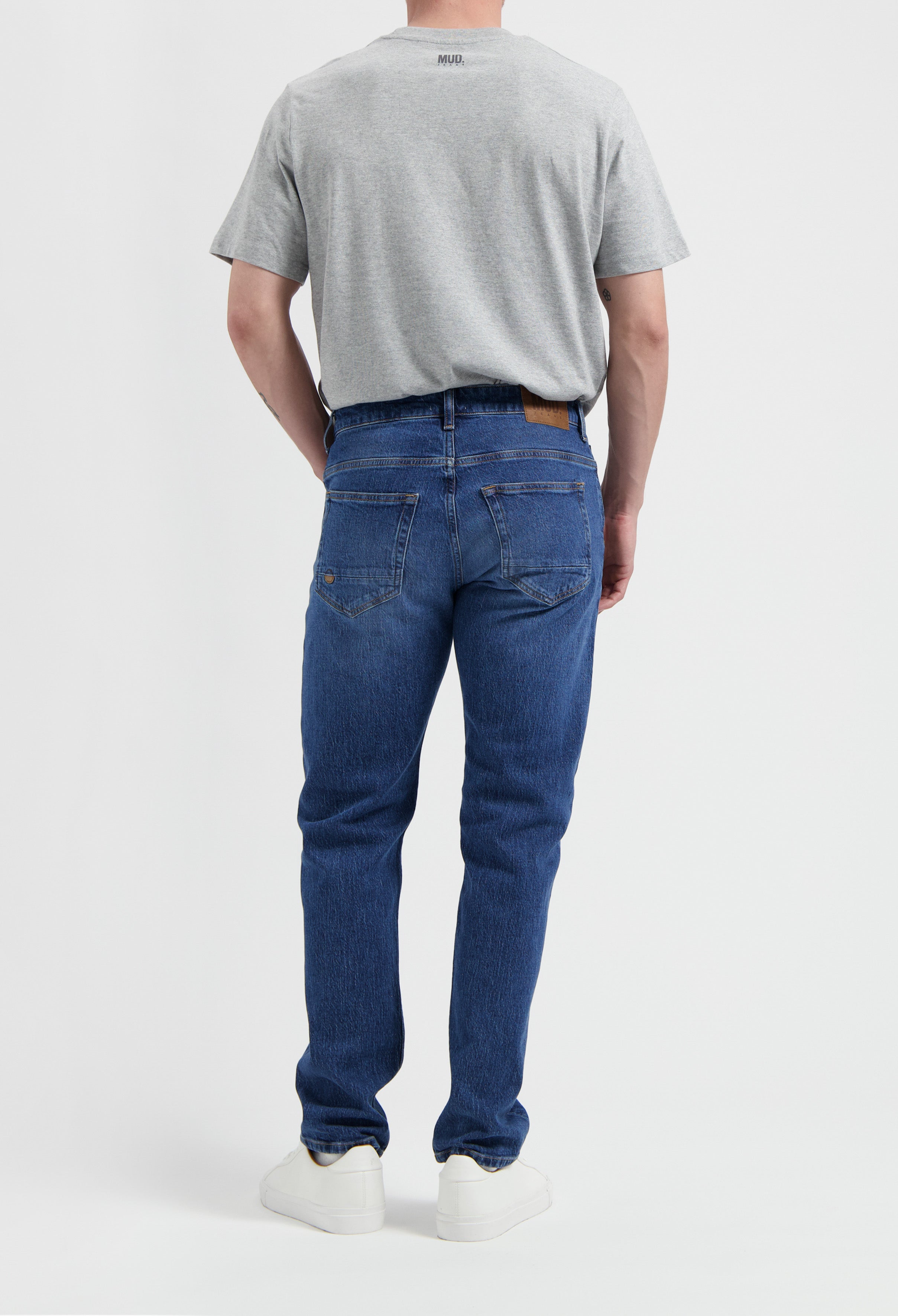 Sustainable MUD Jeans in beige, crafted from organic cotton, offering a slim fit, paired with a casual gray t-shirt.