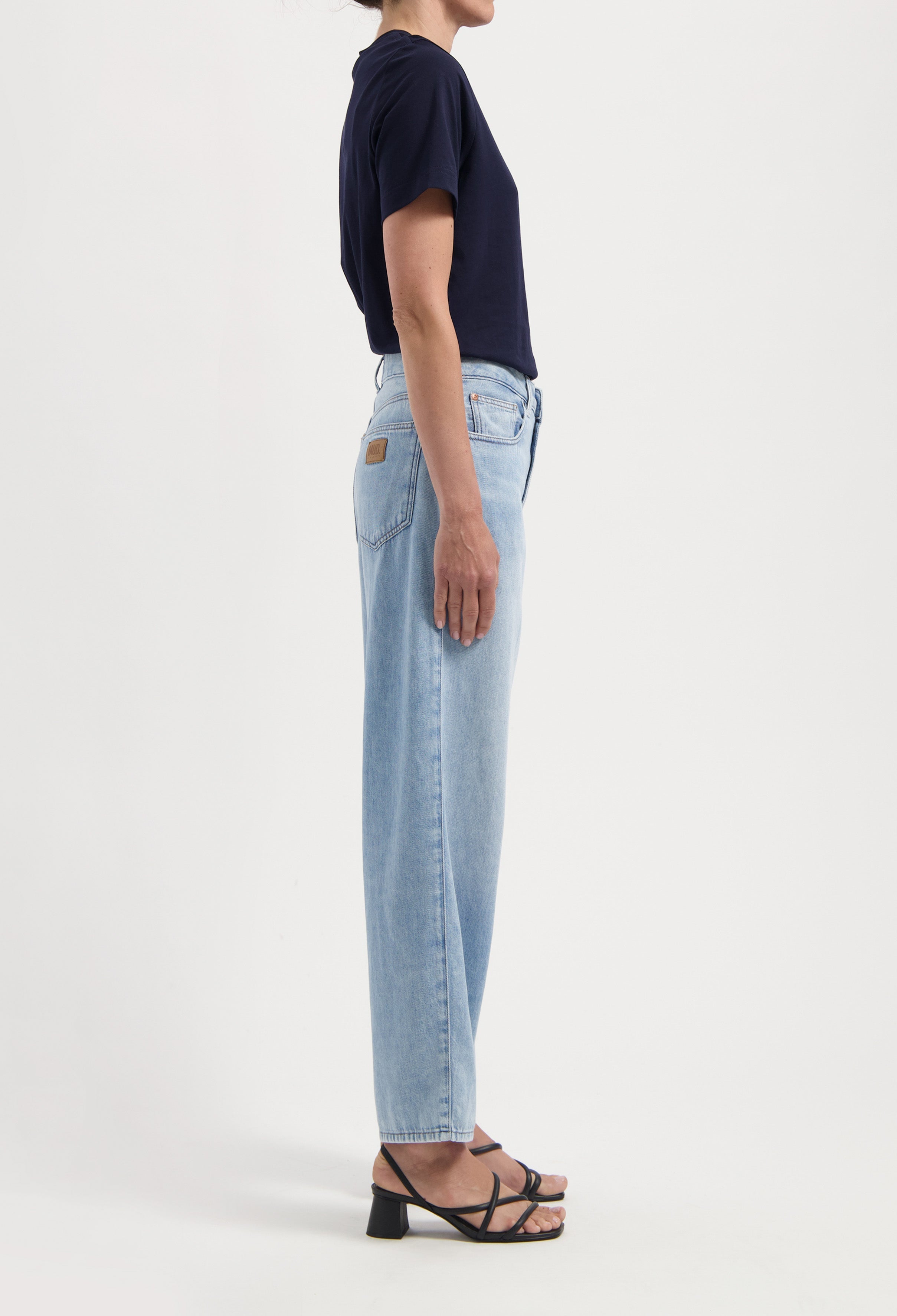 Light blue straight-leg jeans worn with a black short-sleeve top and strappy sandals, showcasing casual summer style.