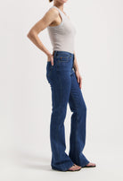 Model wearing a sleeveless beige top with blue high-waisted bootcut jeans, showcasing casual style and fit.